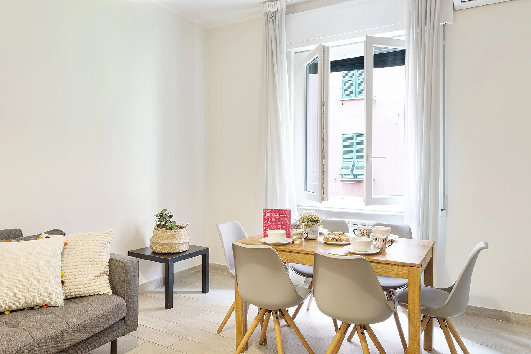 A dining area with a wooden table and light-colored chairs beside a large window.