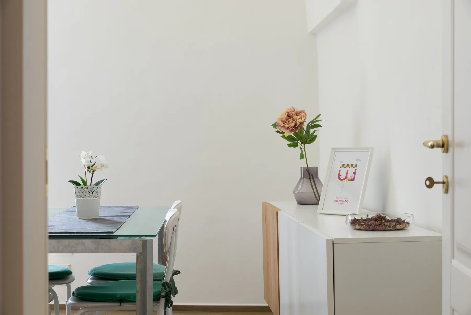 Un comedor con una mesa y un arreglo floral sobre un mueble.