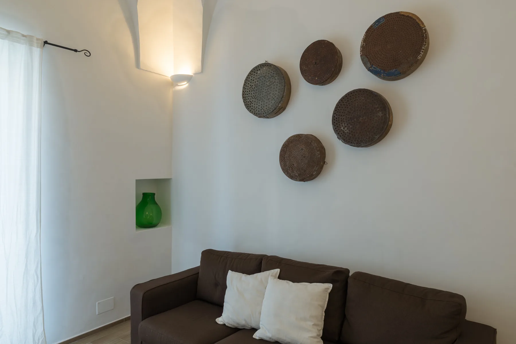 Una sala de estar con un sofá oscuro y decoraciones tejidas en la pared.