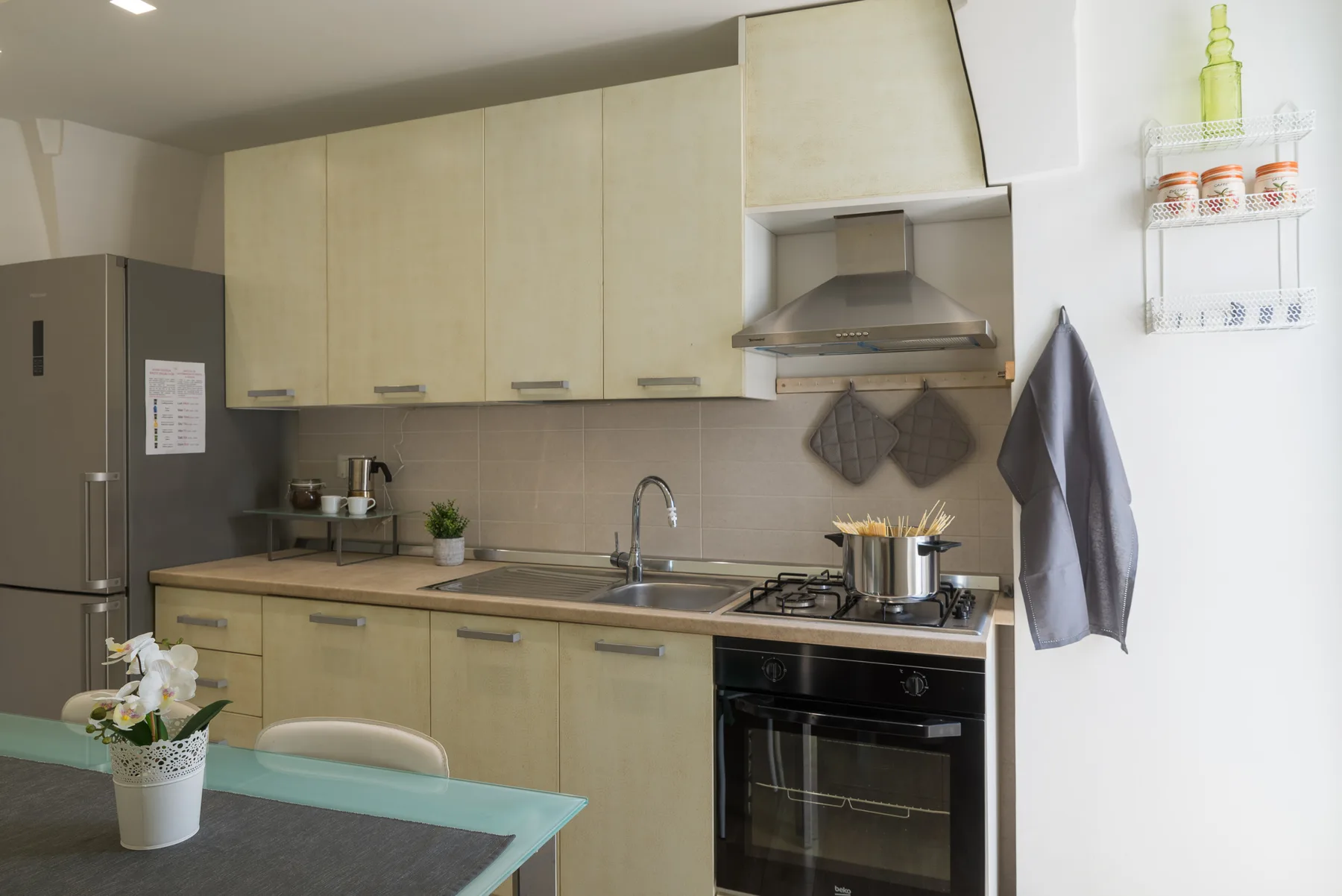 Una cocina con gabinetes claros, una encimera y una estufa bajo una campana extractora.