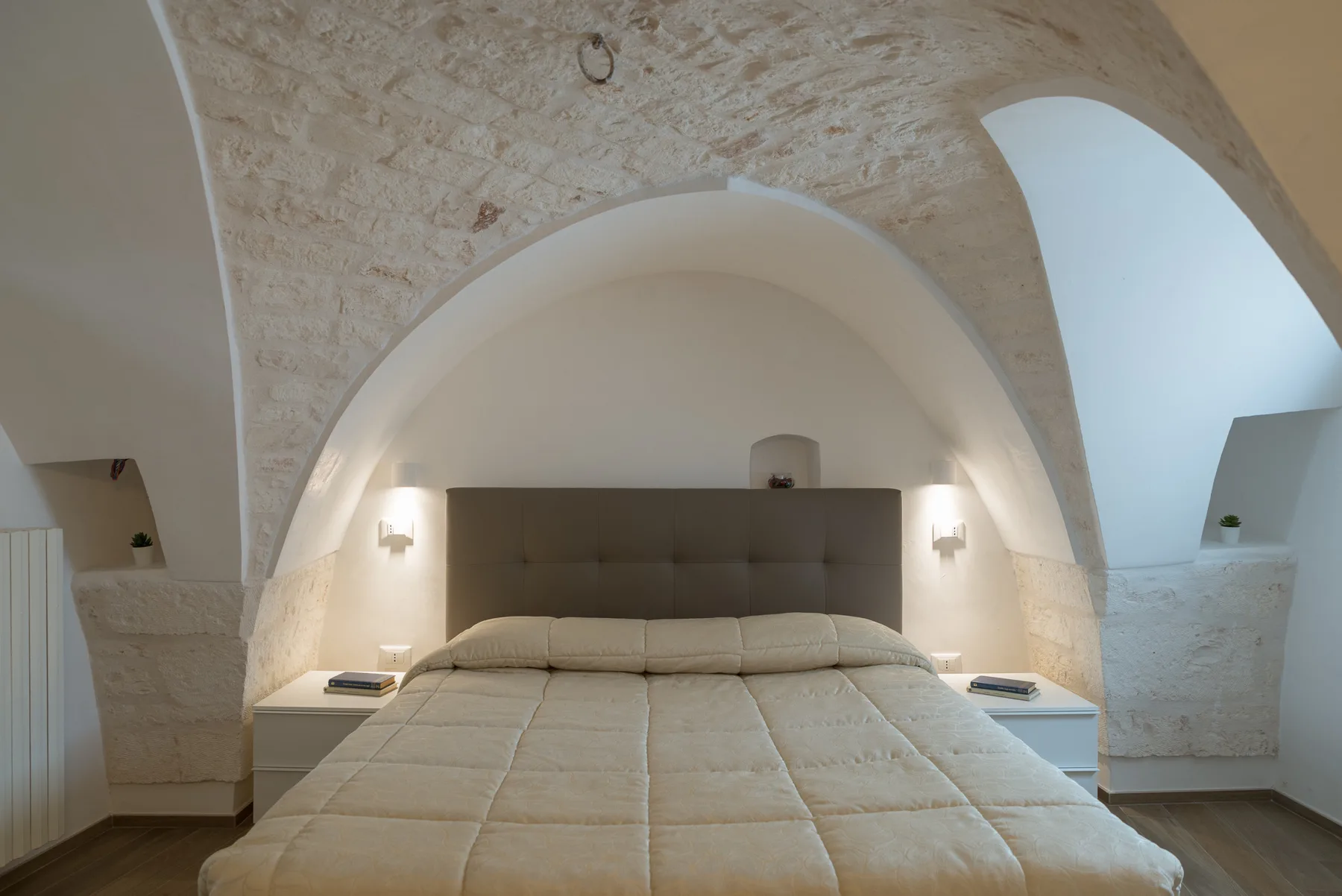 Un dormitorio con una cama bajo un techo curvo de piedra clara.