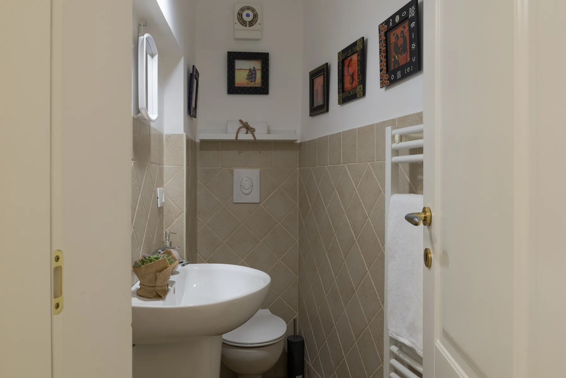 Un baño pequeño con lavabo, inodoro y cuadros enmarcados en las paredes.