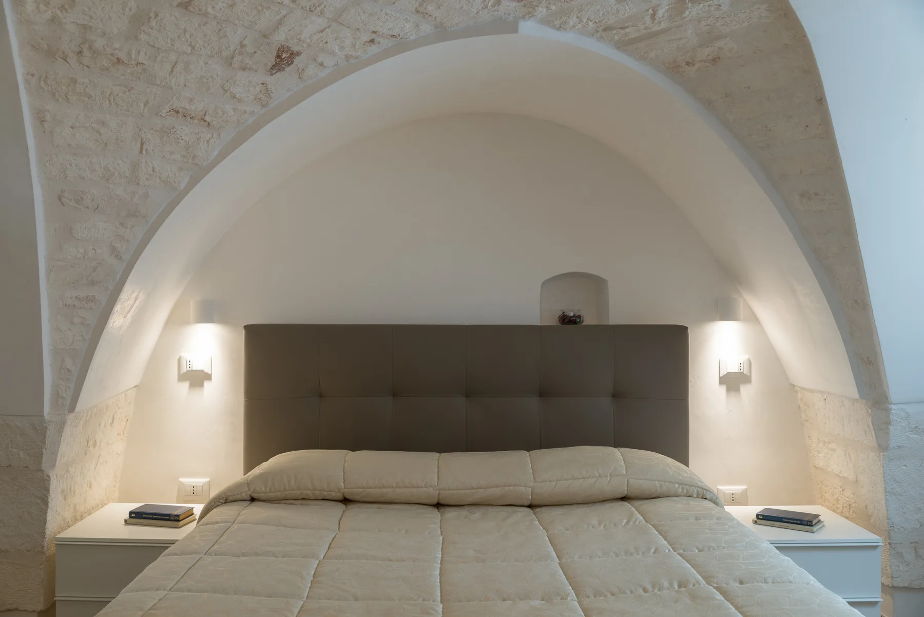 Un dormitorio con una cama grande bajo un techo arqueado.