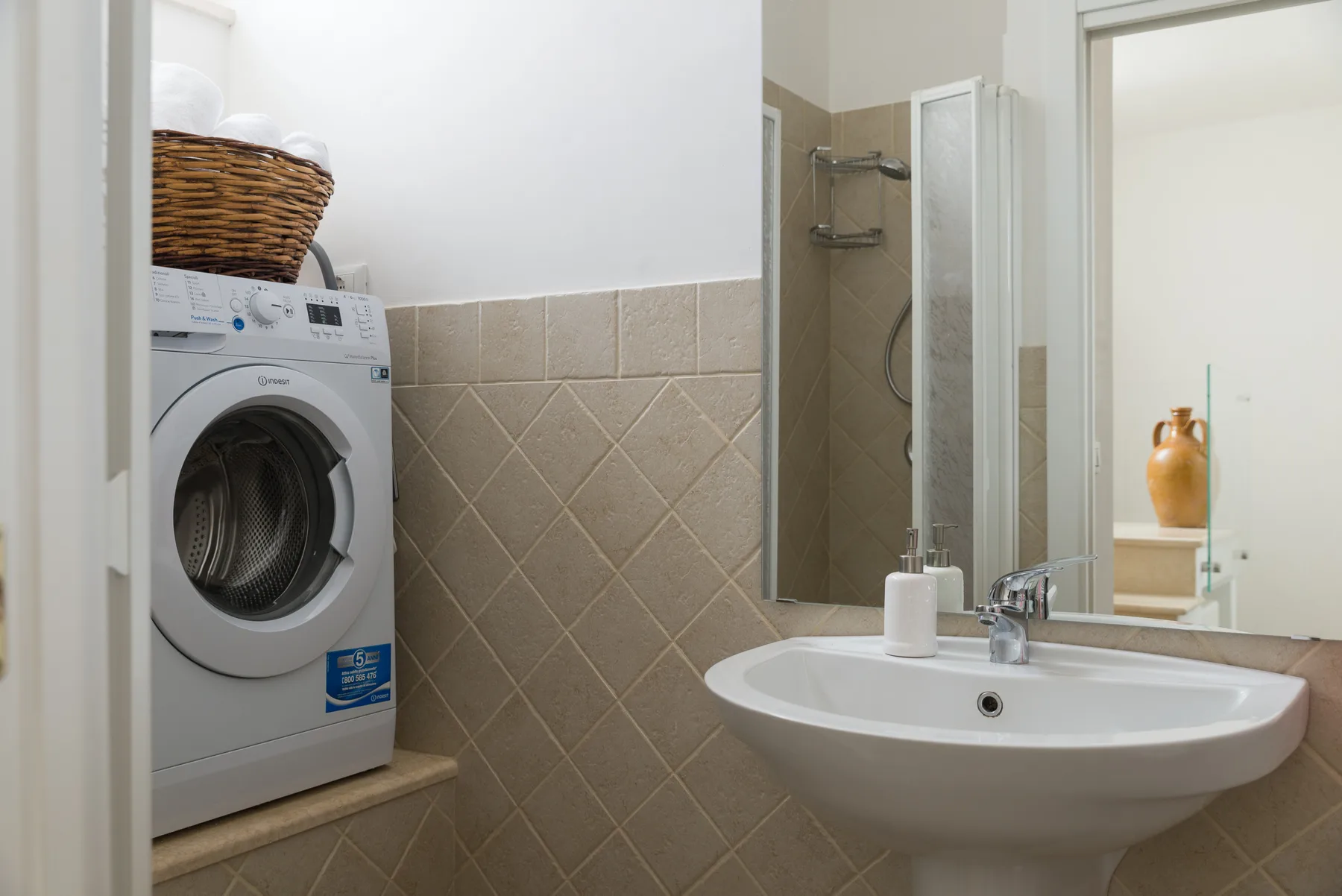 Un baño con lavadora, lavabo y ducha.