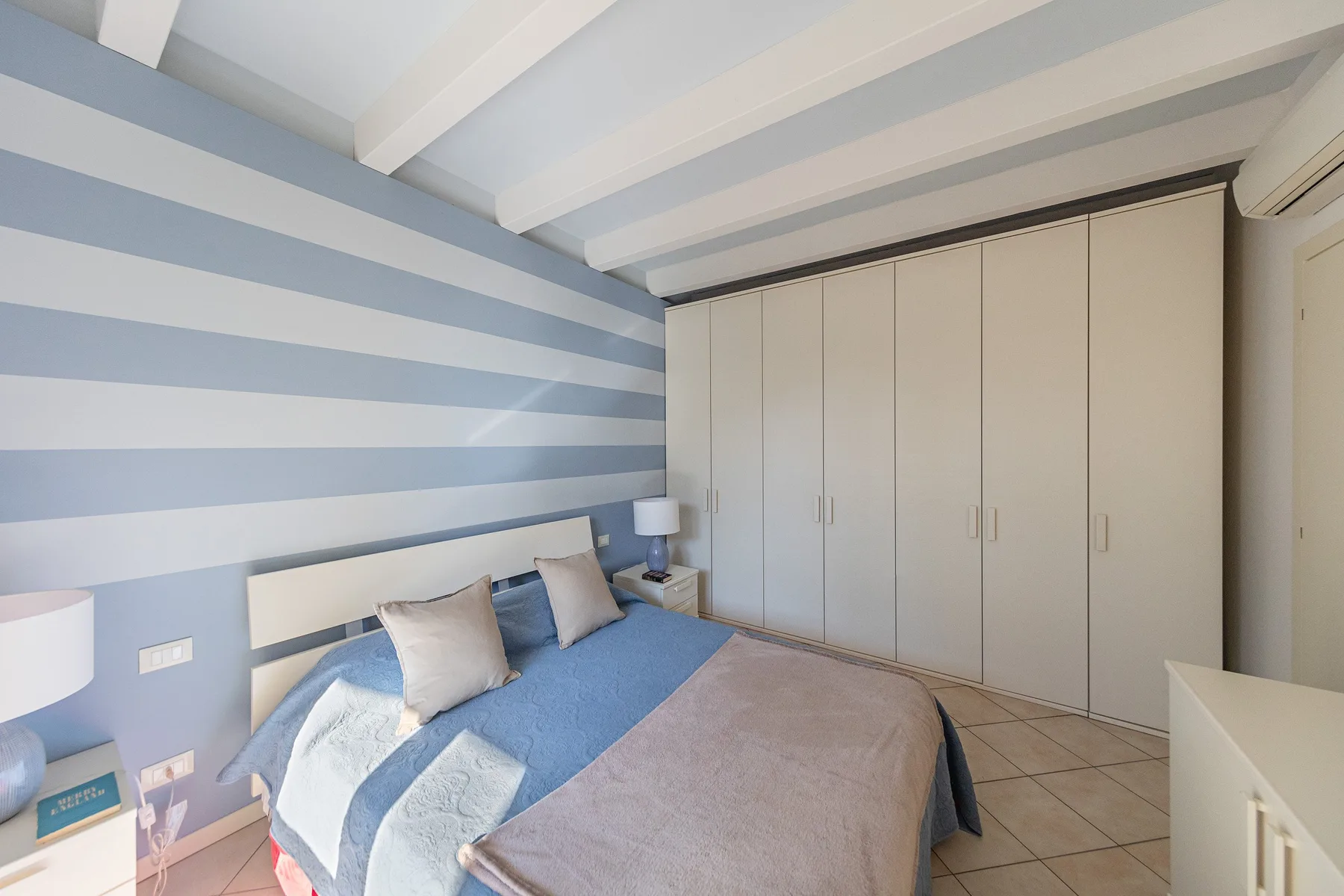 A bedroom with a bed beside a wall of built-in wardrobes.