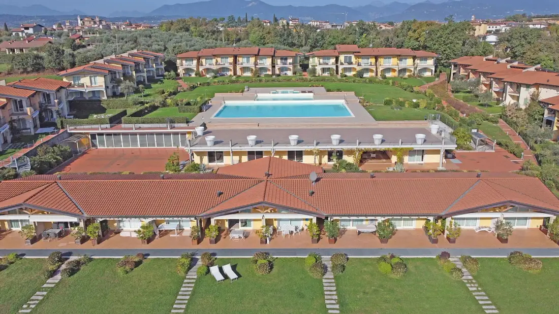 Aerial view of a pool and surrounding buildings amid landscaped grounds.
