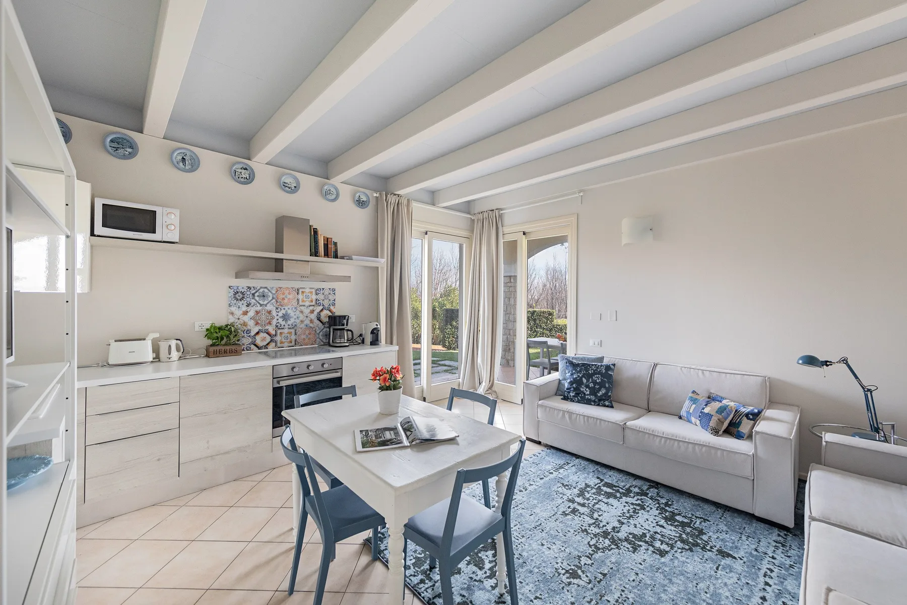 A bright living room with a dining table, kitchenette, and seating area.
