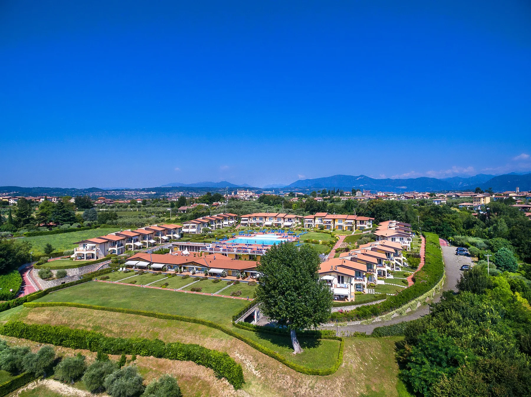 Aerial view of a resort complex with rows of buildings and a swimming pool.