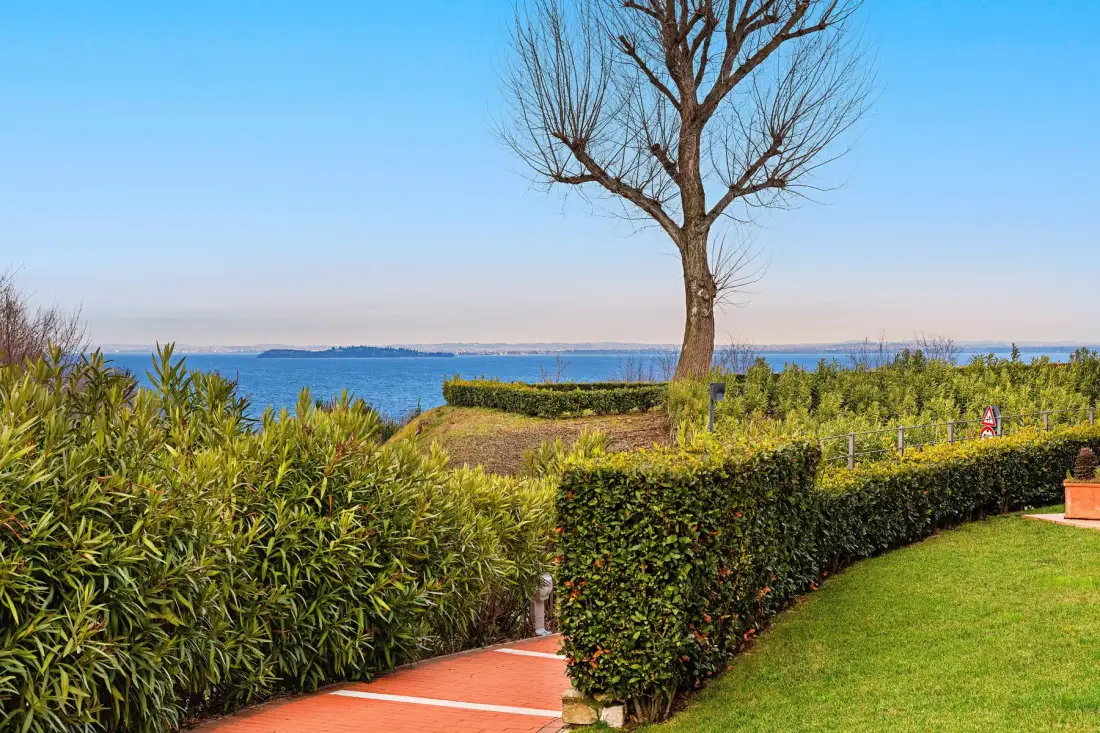 A garden path runs between trimmed hedges toward a view of the sea.