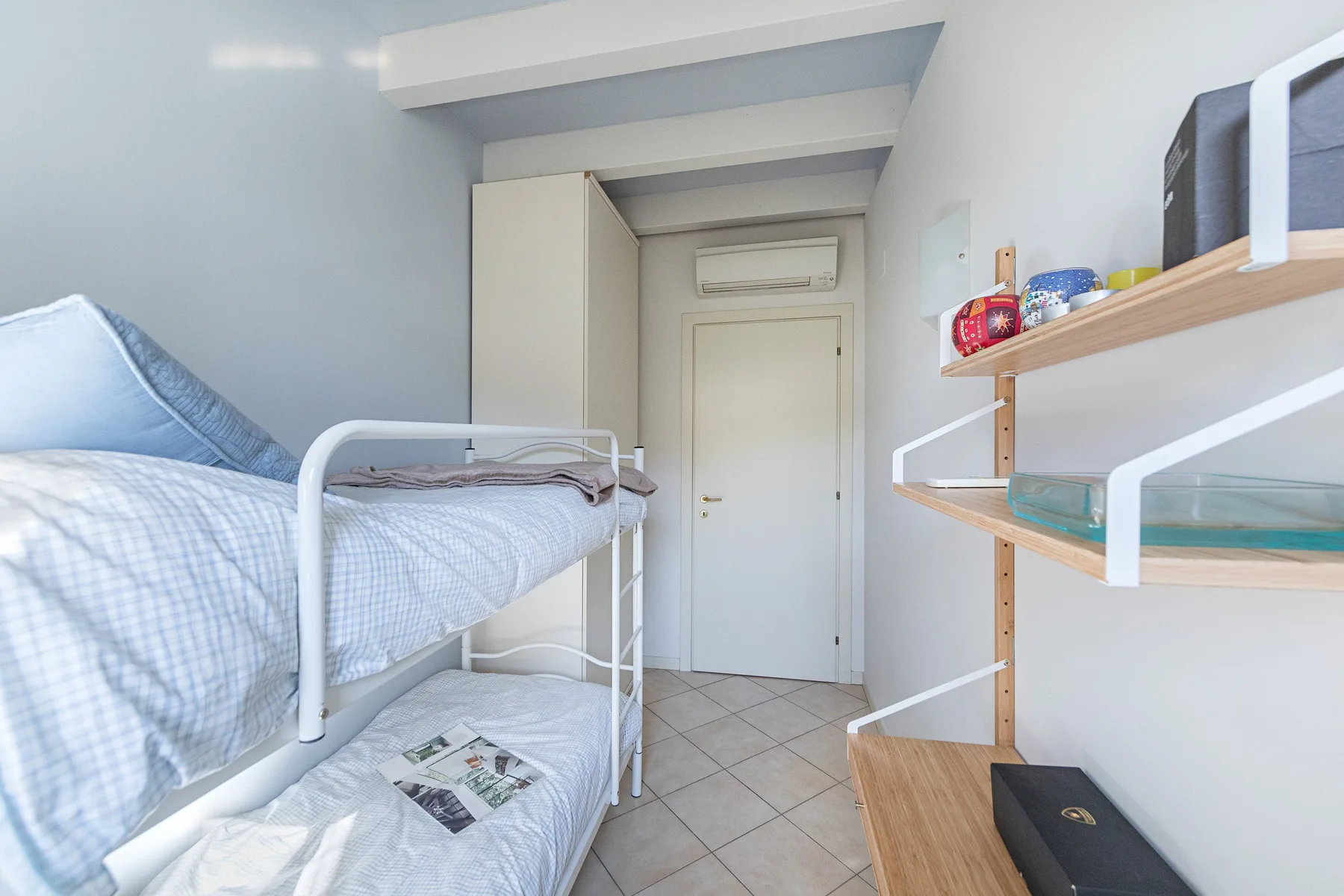 A compact bedroom with bunk beds, a wardrobe, and a desk.