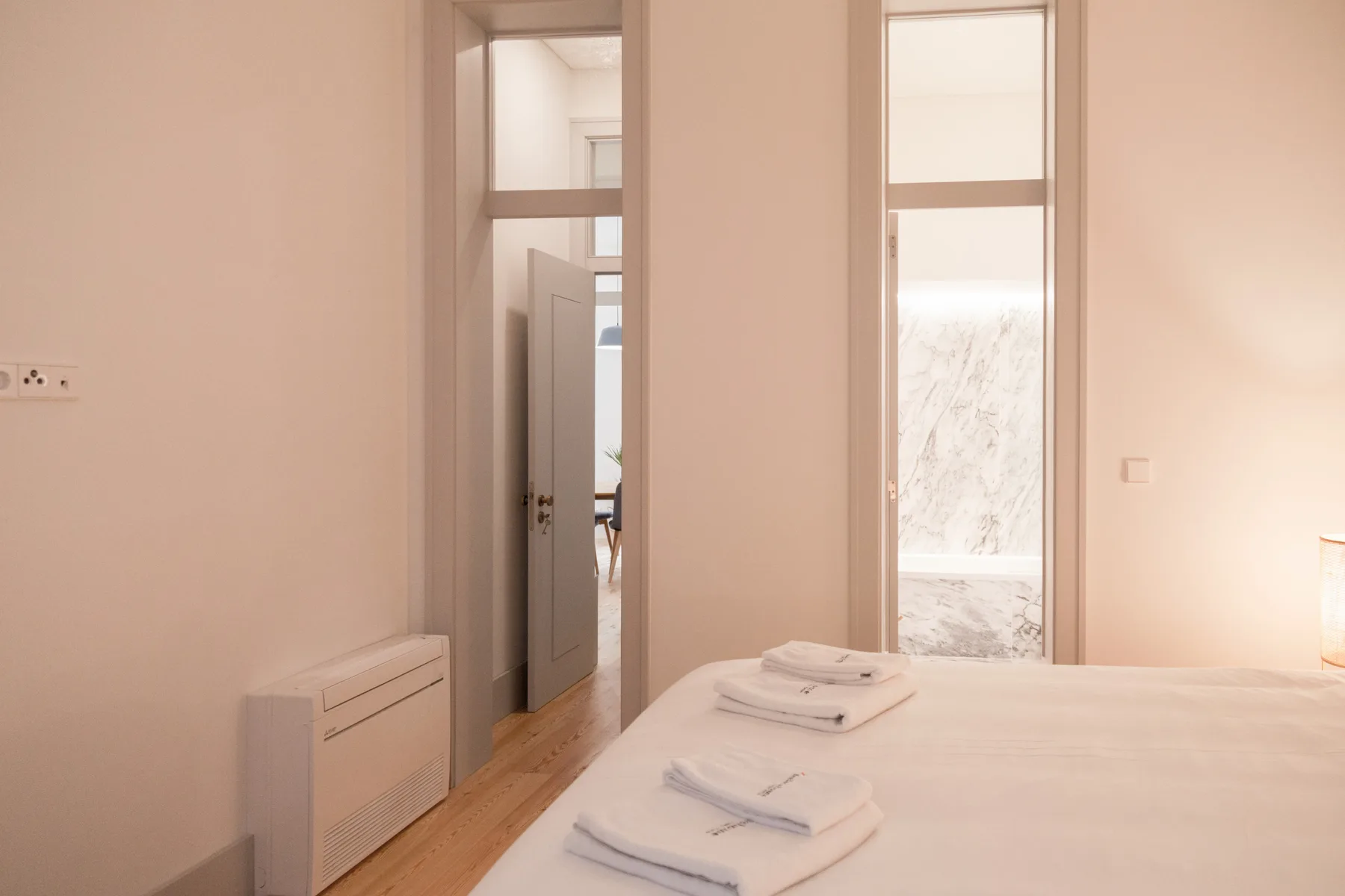A bright bedroom with a neatly made bed and folded towels.