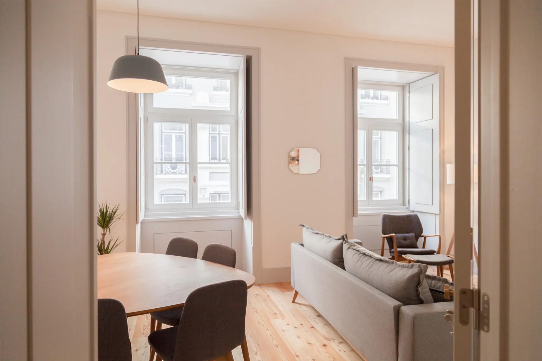 A bright living and dining area with seating, a table, and tall windows.