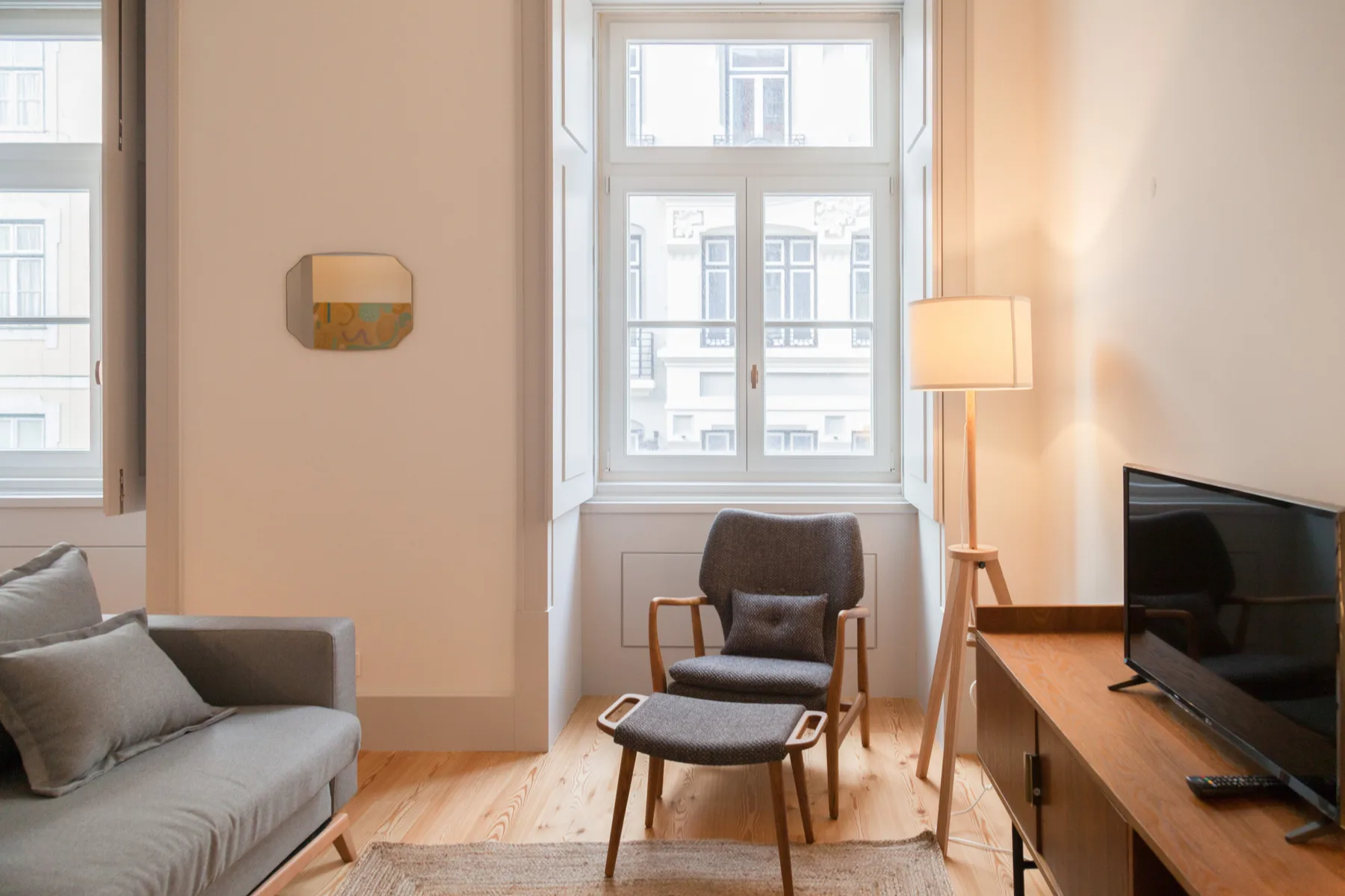 A bright living room with seating, a television, and tall windows.