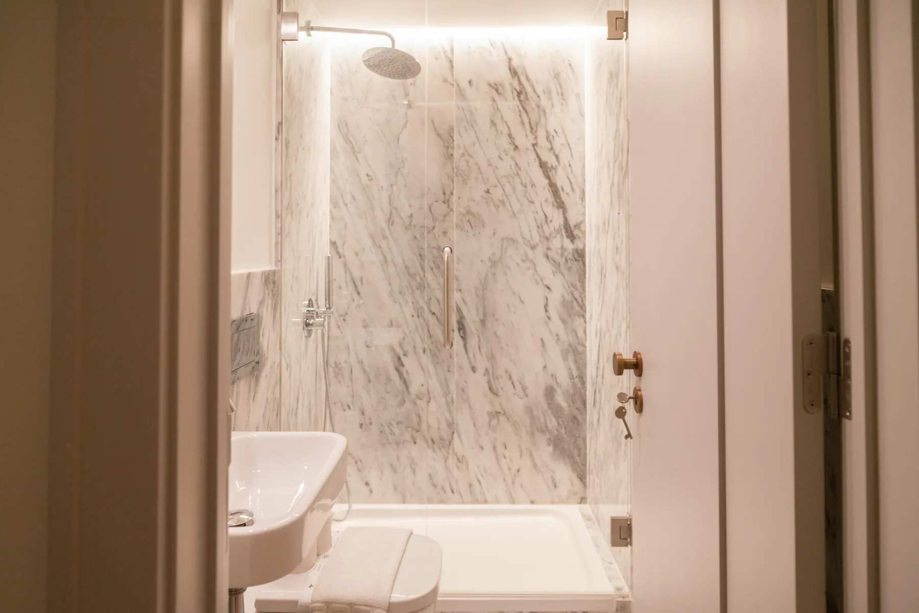 A bathroom with a bathtub, sink, and marble-patterned wall.
