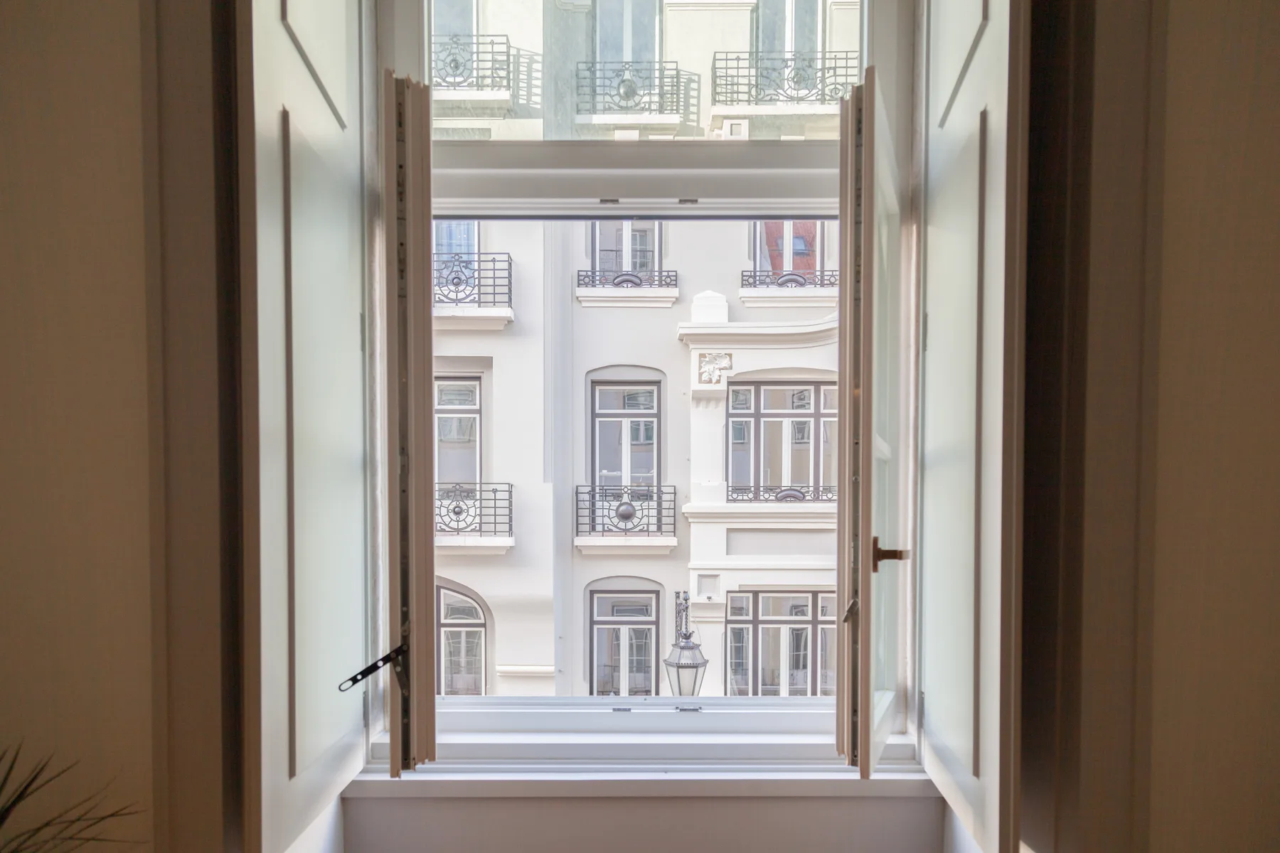 An open window looks onto a neighboring building with balconies.