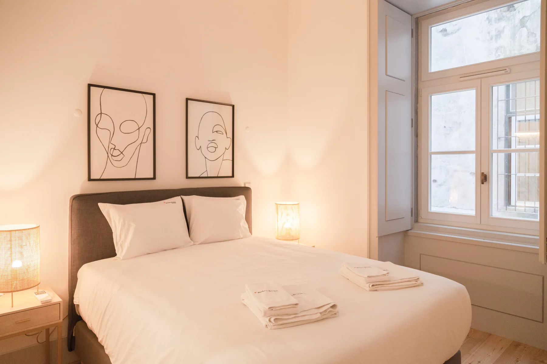 A bedroom with a neatly made bed and framed artwork above the headboard.