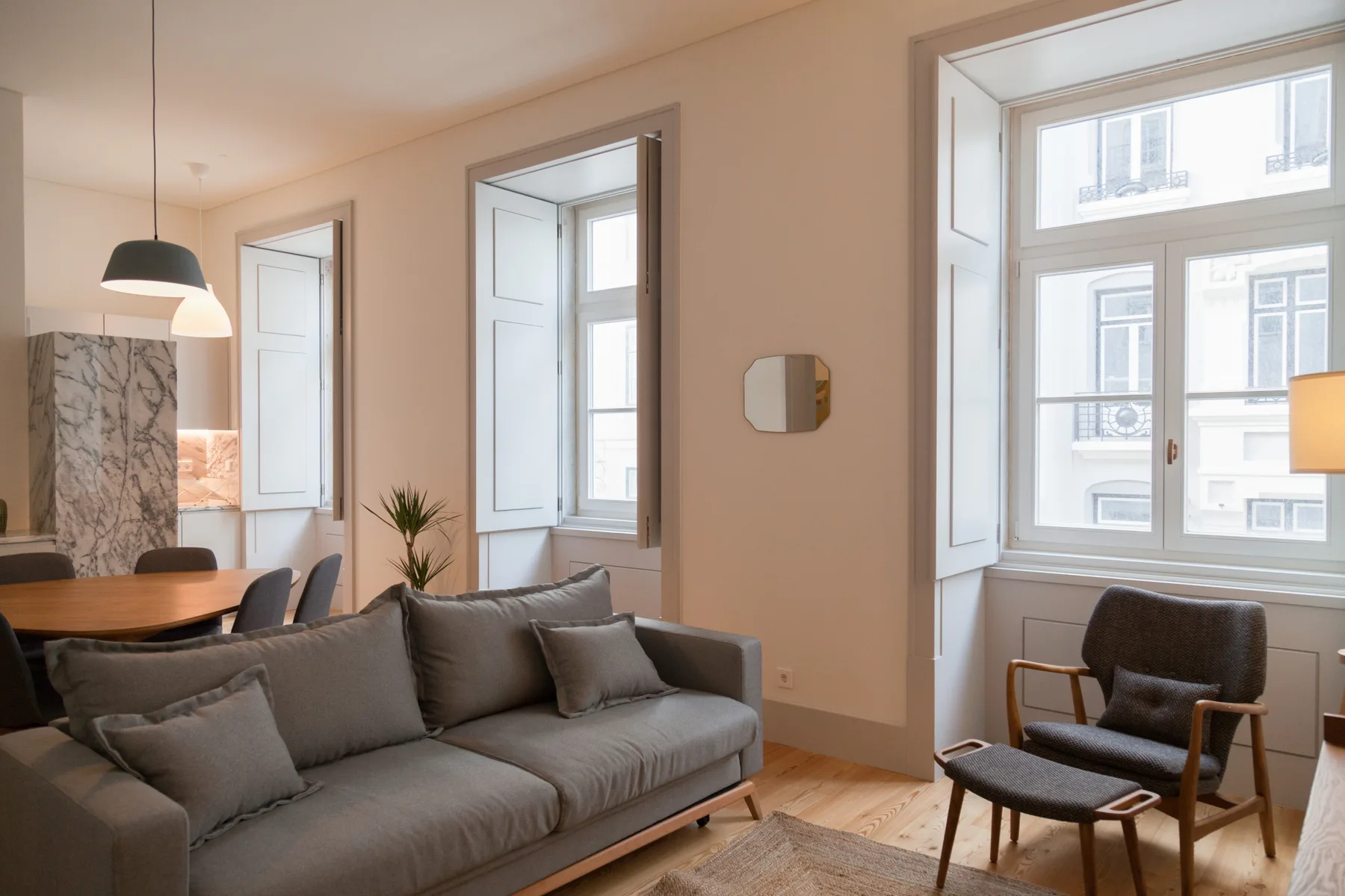 A living room with seating, a dining table, and large windows.