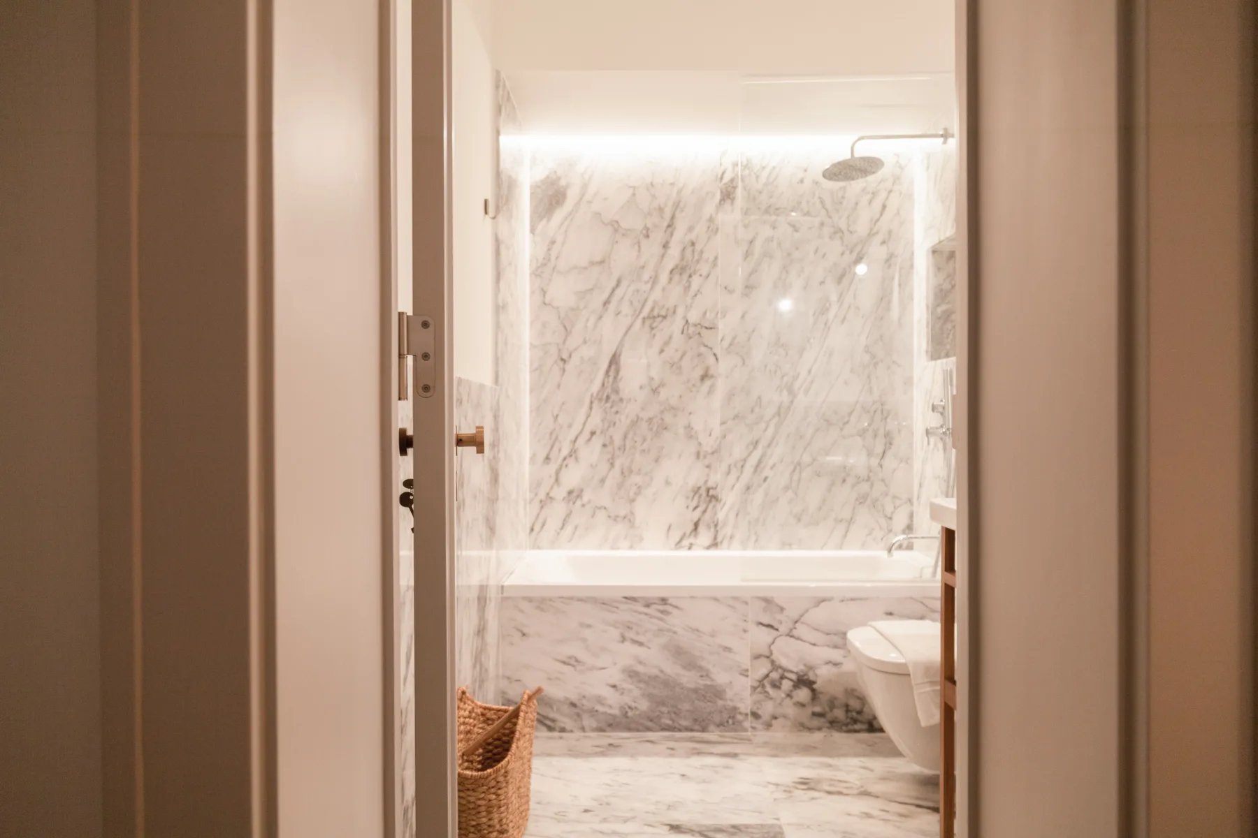 A marble-tiled bathroom with a shower and part of a toilet visible.