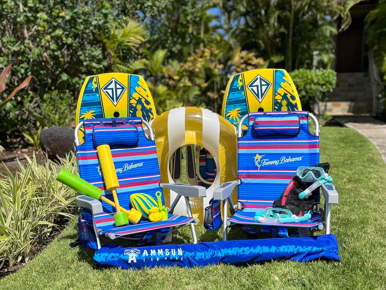 Two colorful beach chairs and water-sports gear sit on a lawn.
