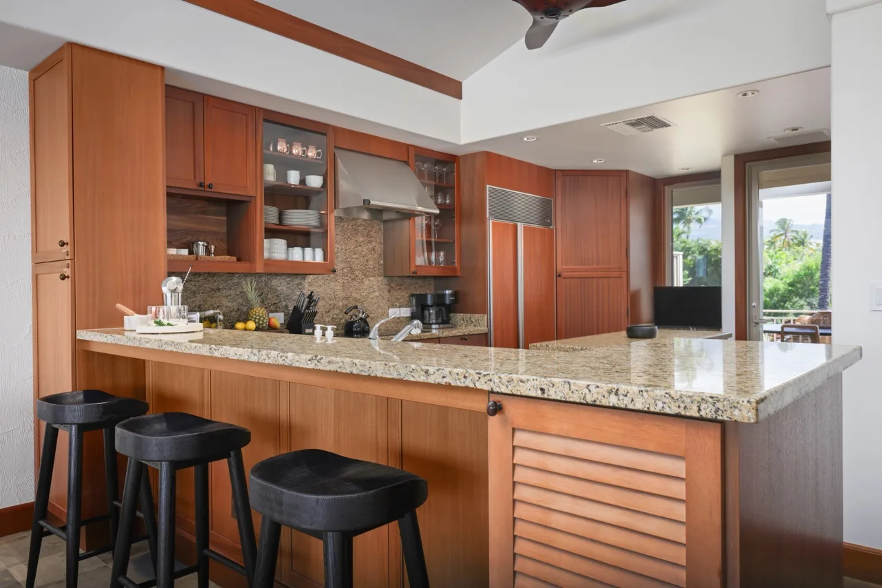 A kitchen with wooden cabinetry and a wide stone countertop.