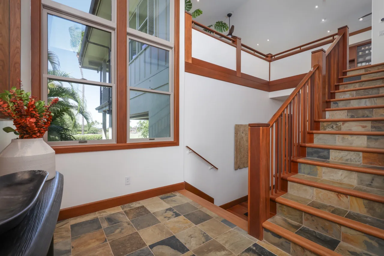 A bright stair hall with a large window and wooden stairs.
