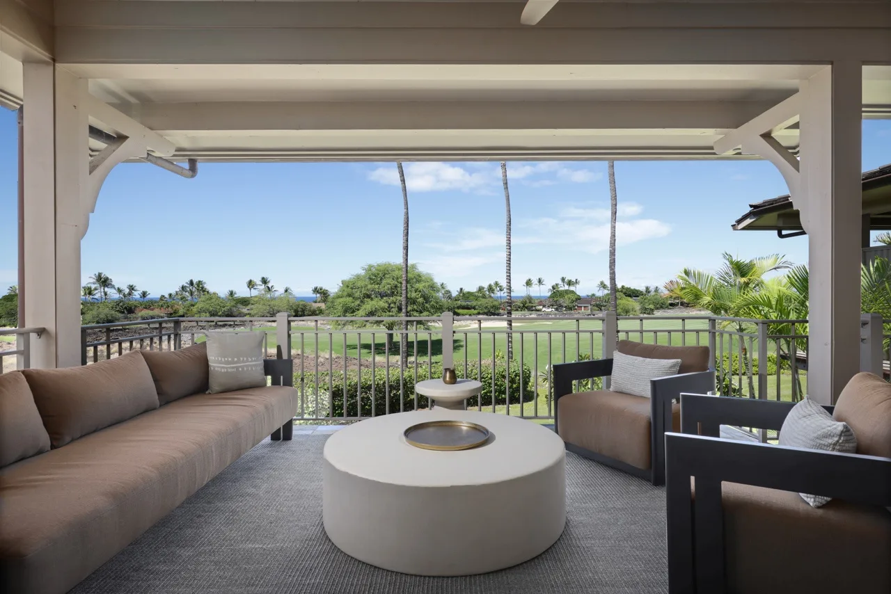 A covered outdoor seating area overlooks a green landscape beneath a blue sky.