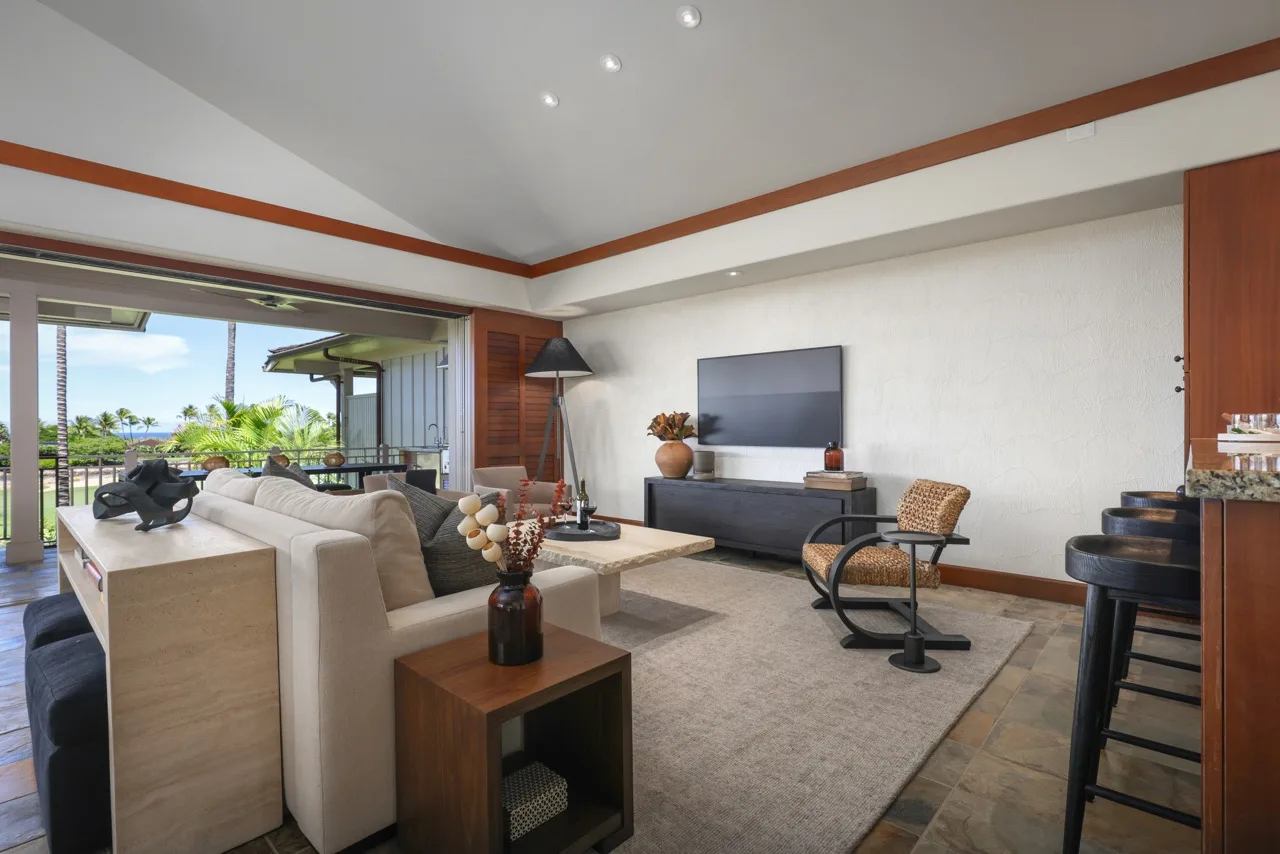 A living room with seating, a television, and an open view to a patio.