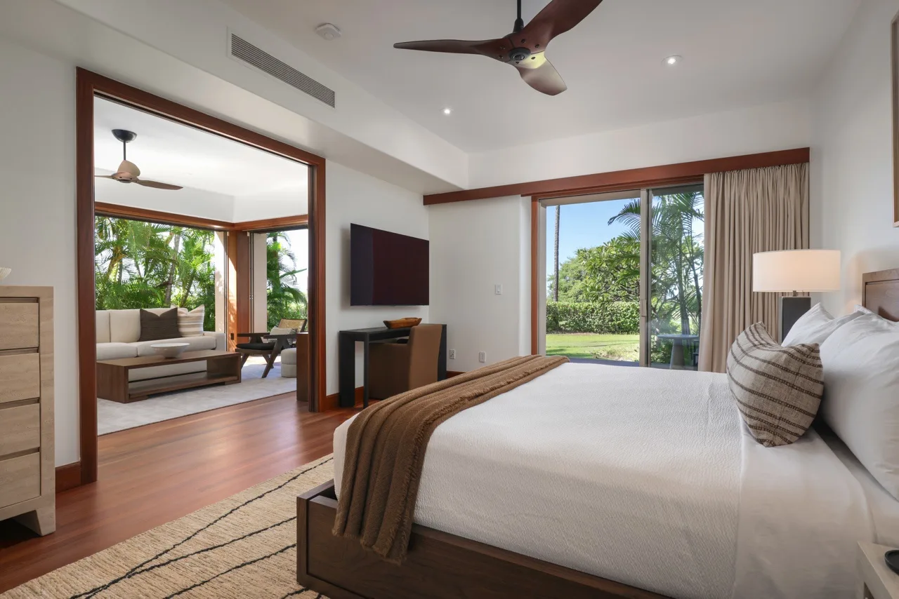 A bedroom with a large bed and sliding glass doors opening onto a garden.