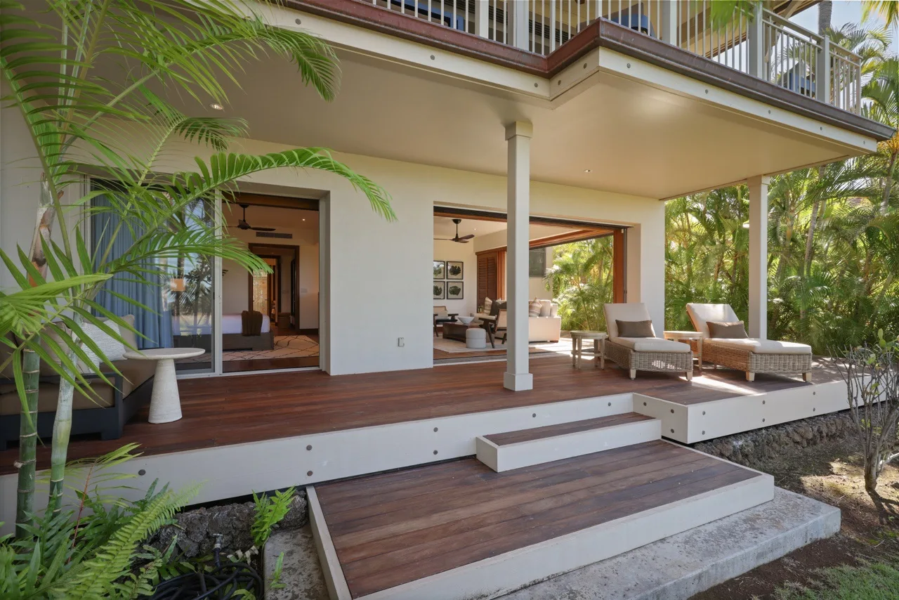 A covered outdoor patio with seating opens onto a garden.