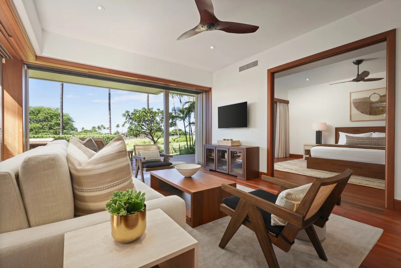 A living area opens onto a garden, with a bedroom visible through the doorway.