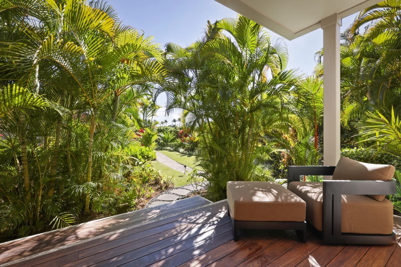 A covered outdoor seating area overlooks lush tropical gardens and a winding path.