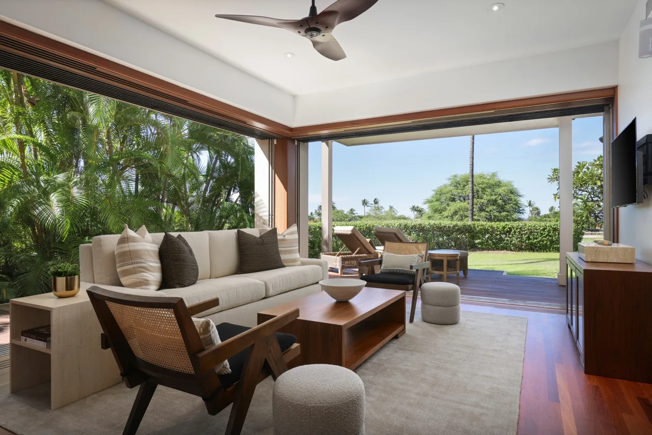 A bright living room opens onto a garden through wide glass doors.