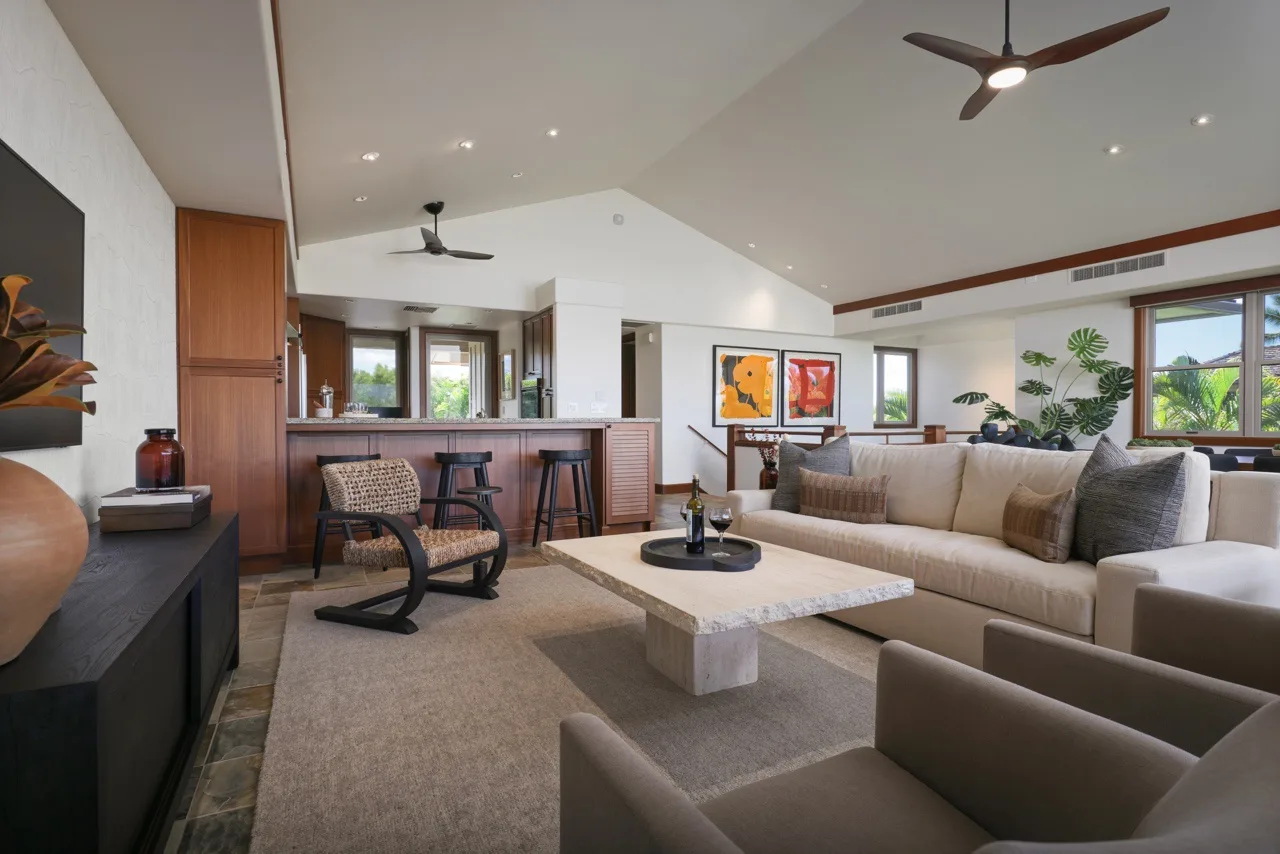 A bright living room with a seating area, coffee table, and ceiling fans.