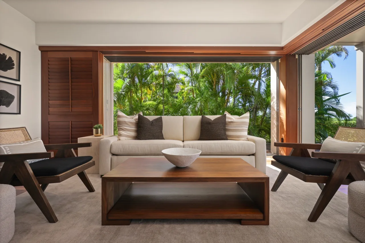 A living room with a sofa, a wooden coffee table, and a garden view.
