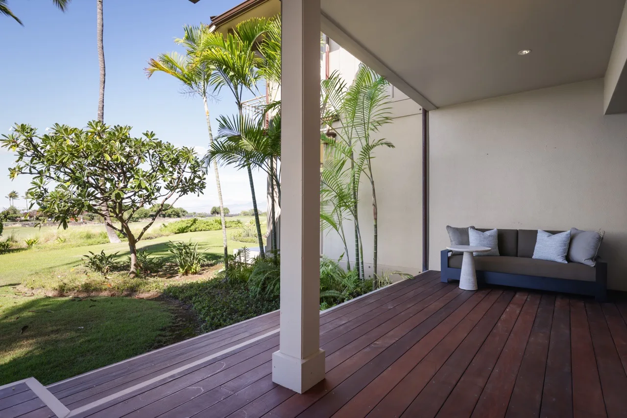 A covered patio with outdoor seating overlooks a landscaped garden.