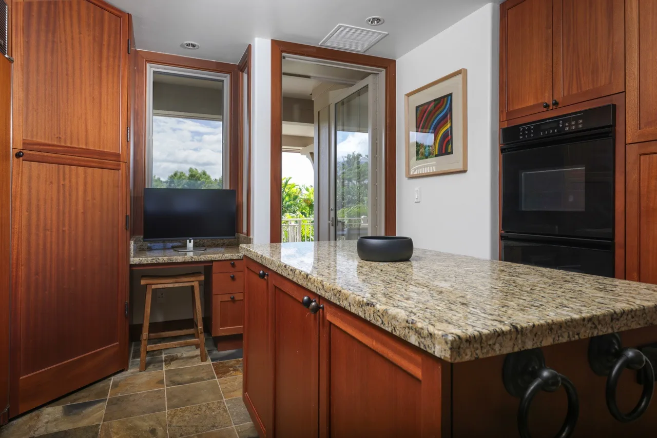 A kitchen with wooden cabinets, a stone countertop, and a built-in oven.