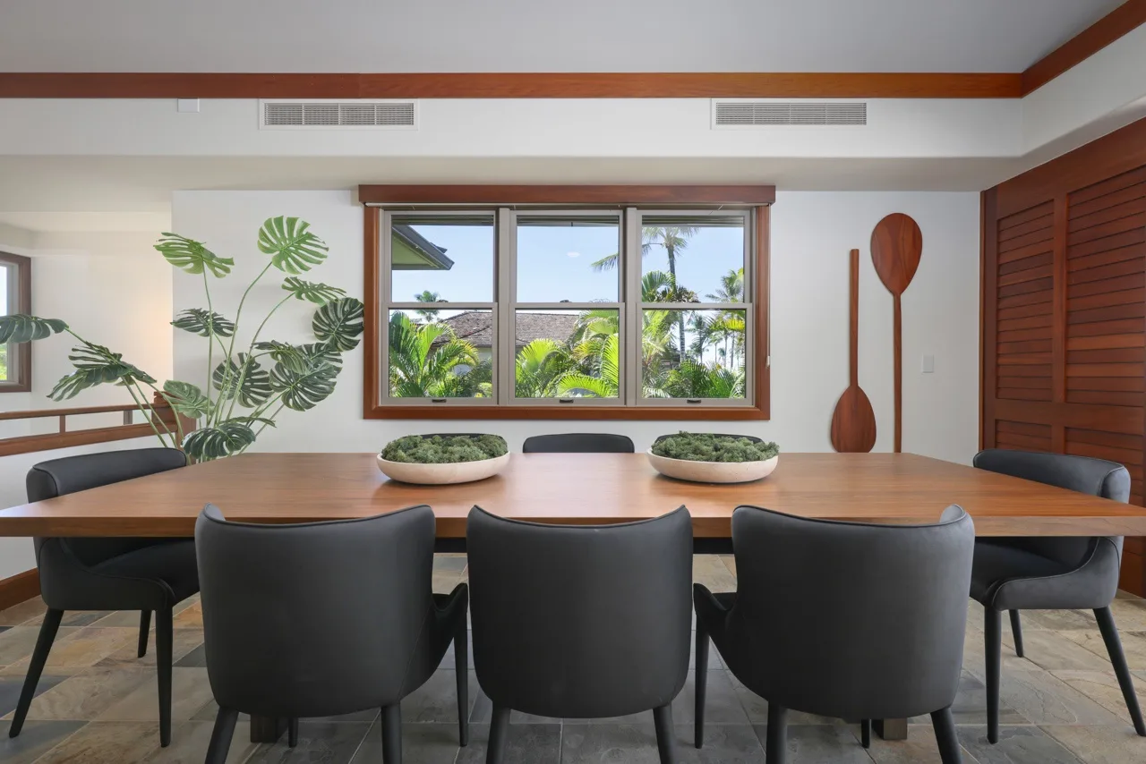 A dining area with a long table and chairs in front of a large window.