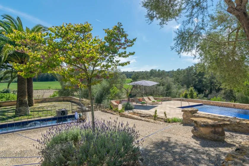 An outdoor pool and sunbathing area overlook a green countryside landscape.