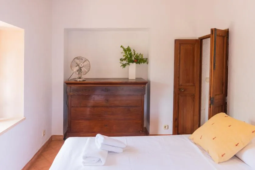 A bedroom with a wooden dresser, a bed, and an open doorway.