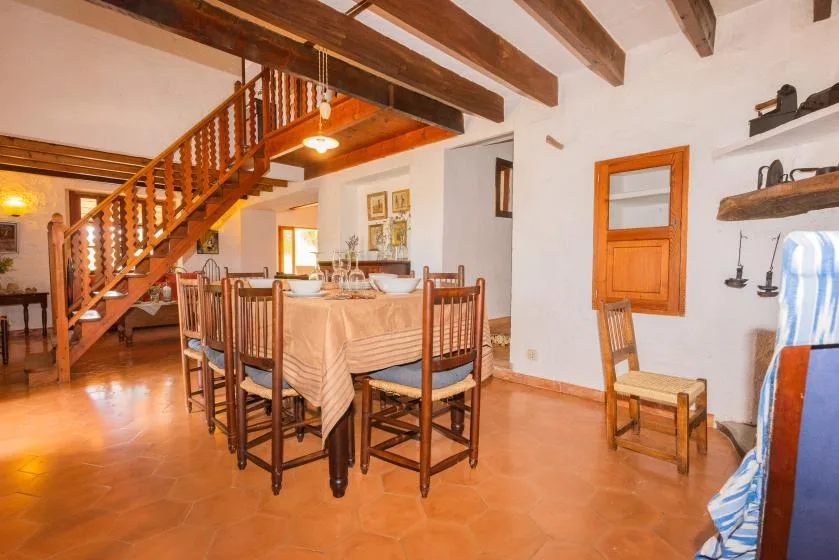 A dining area with a table and chairs sits beneath a wooden staircase.