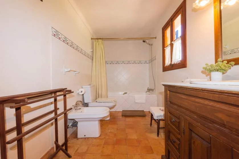 A bathroom with a bathtub, toilet, and wooden vanity.