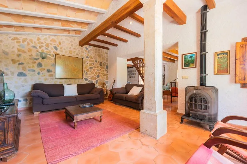 A living room with seating, a coffee table, and exposed wooden ceiling beams.