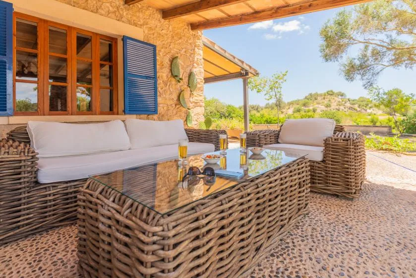 A covered outdoor seating area with woven furniture and a glass coffee table.