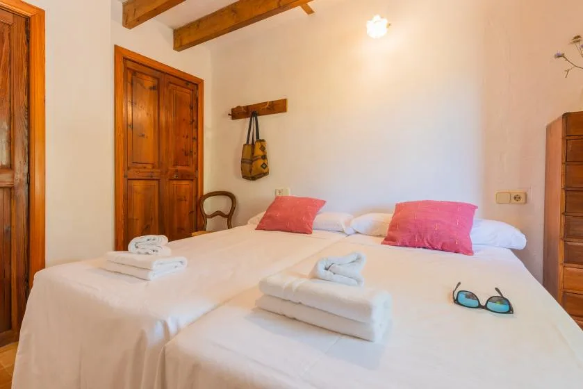 A bedroom with two beds, pink pillows, and folded towels.