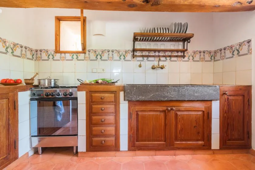 A rustic kitchen with wooden cabinets, a stove, and a dish rack.