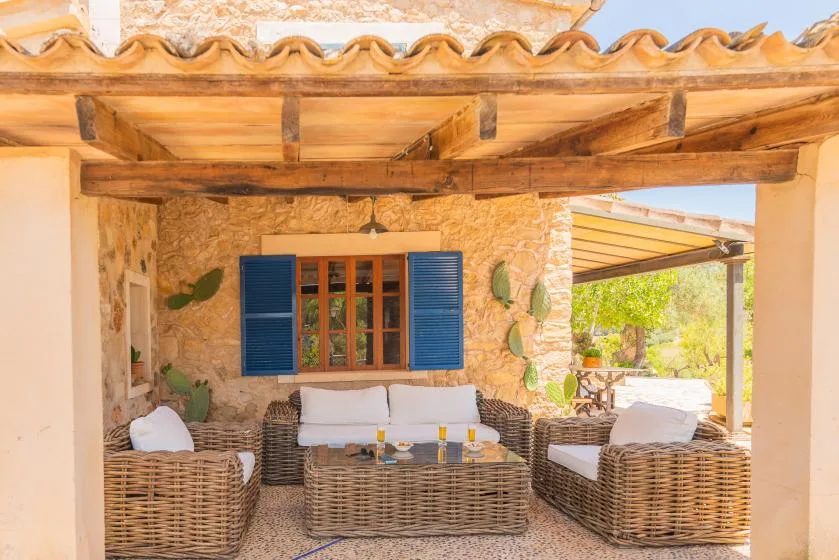 A covered outdoor seating area with wicker furniture and blue shutters.