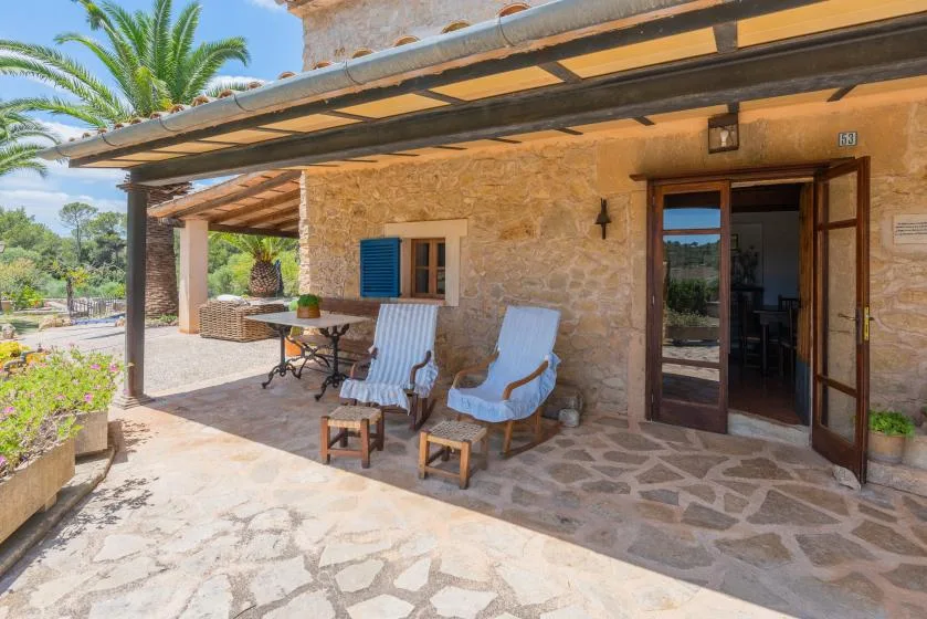 A stone house patio with cushioned seating beneath a wooden pergola.