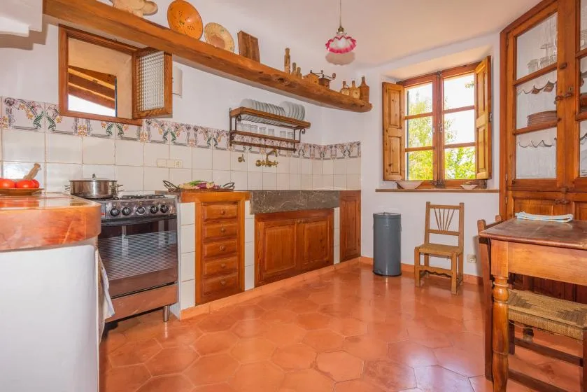 A spacious kitchen with wooden cabinets, a stove, and a large window.