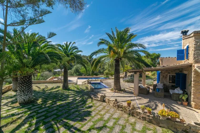 A palm-filled courtyard with a small pool beside a stone building.