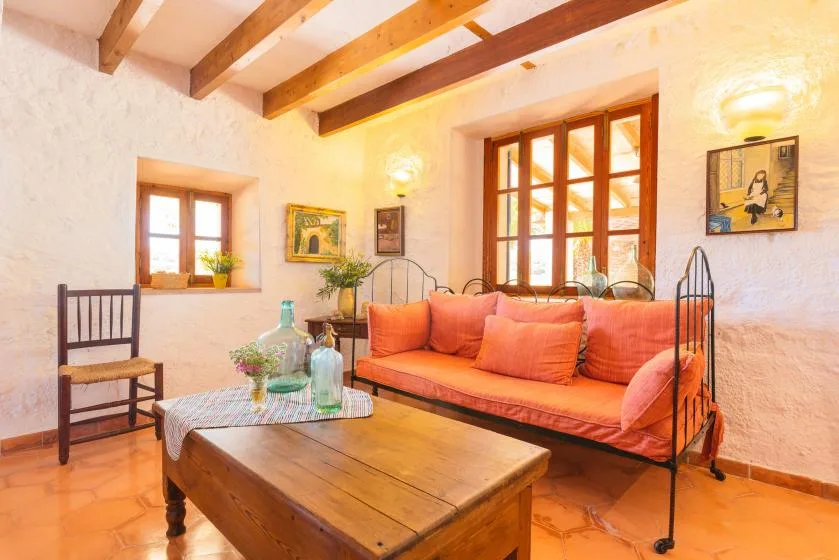 A living room with orange seating and exposed wooden ceiling beams.